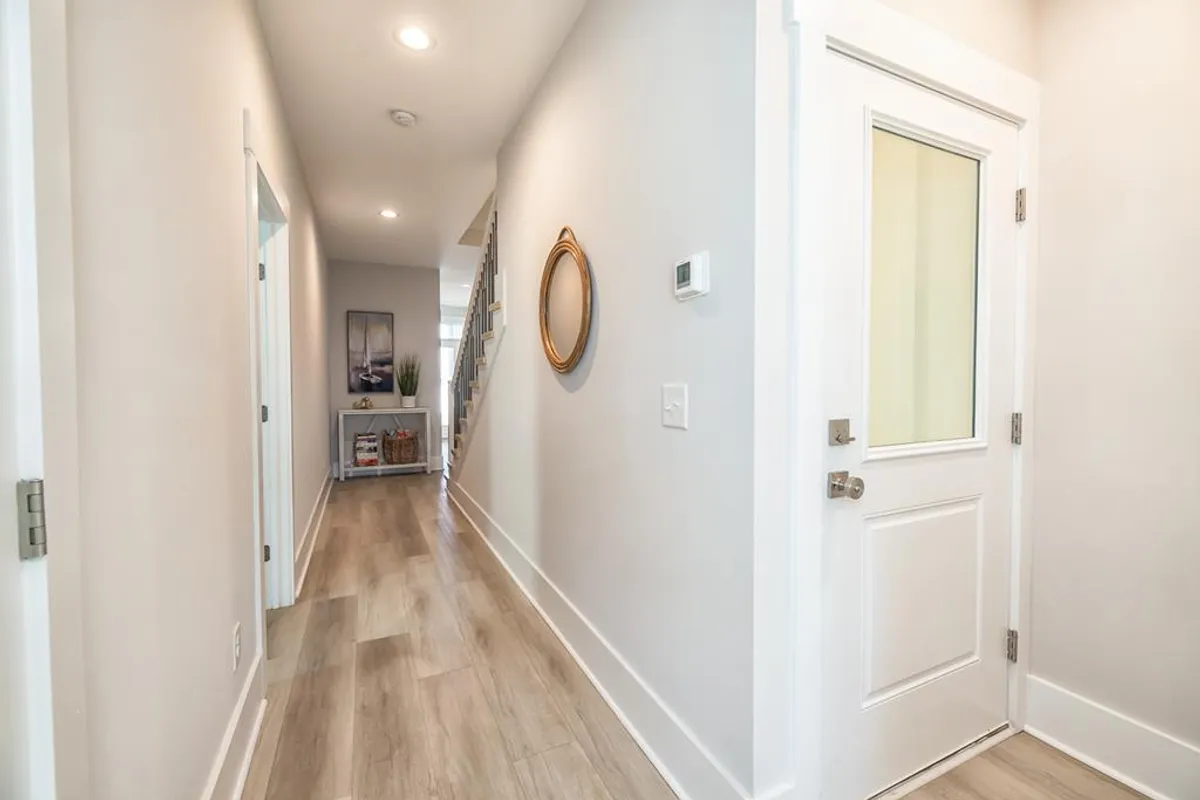 The home’s entryway with a front door, mirror, decorative plant, and staircase creates a welcoming atmosphere. Natural light spills in, enhancing the sense of arrival. The entry hints at easy transitions between inside and outside, setting the stage for the marina lifestyle right outside the door.