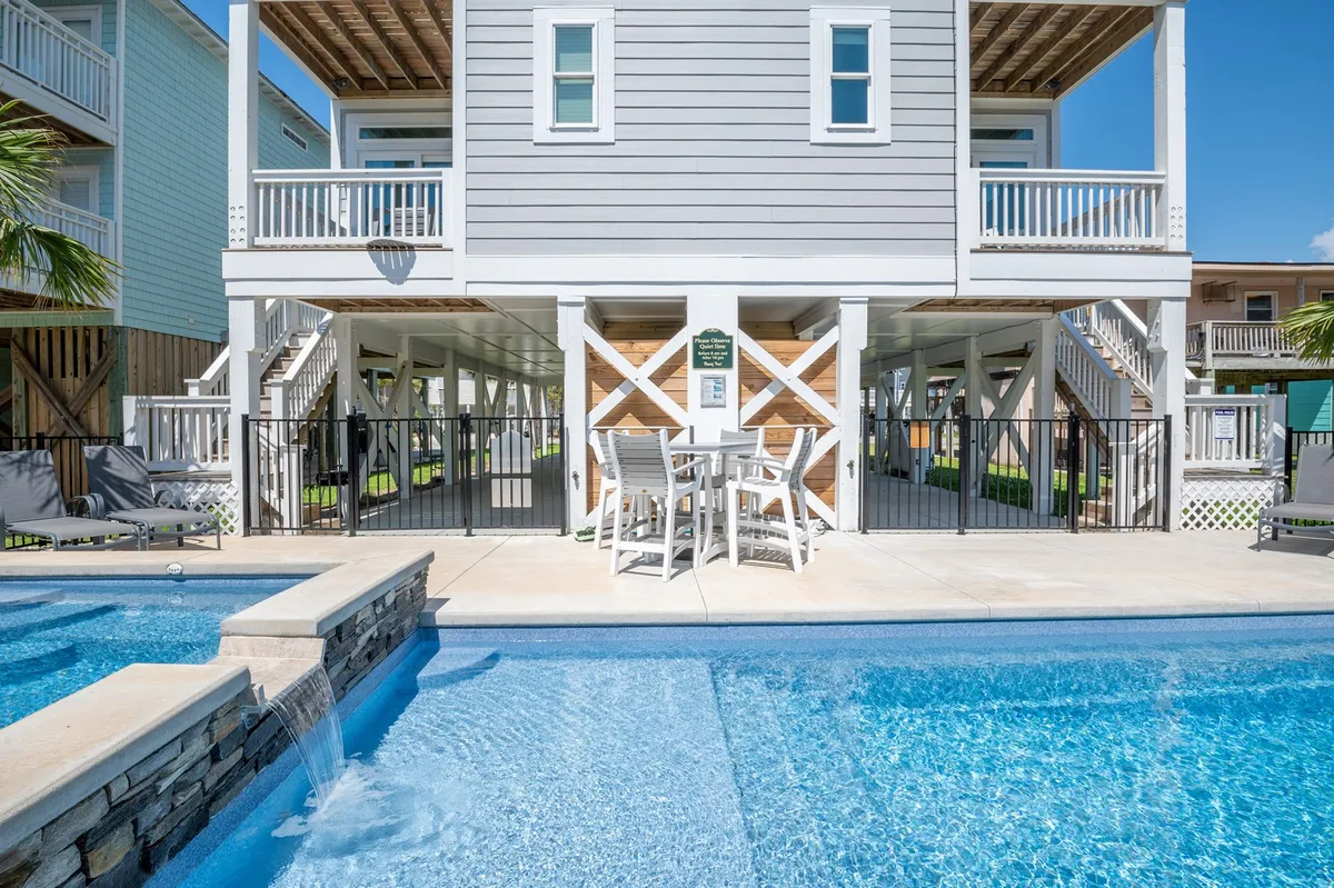 A sparkling swimming pool is the centerpiece of the patio, surrounded by comfortable lounge furniture. The house structure forms a backdrop, blending relaxation with easy outdoor living. The scene radiates the promise of sunny afternoons, swim sessions, and social gatherings by the pool.