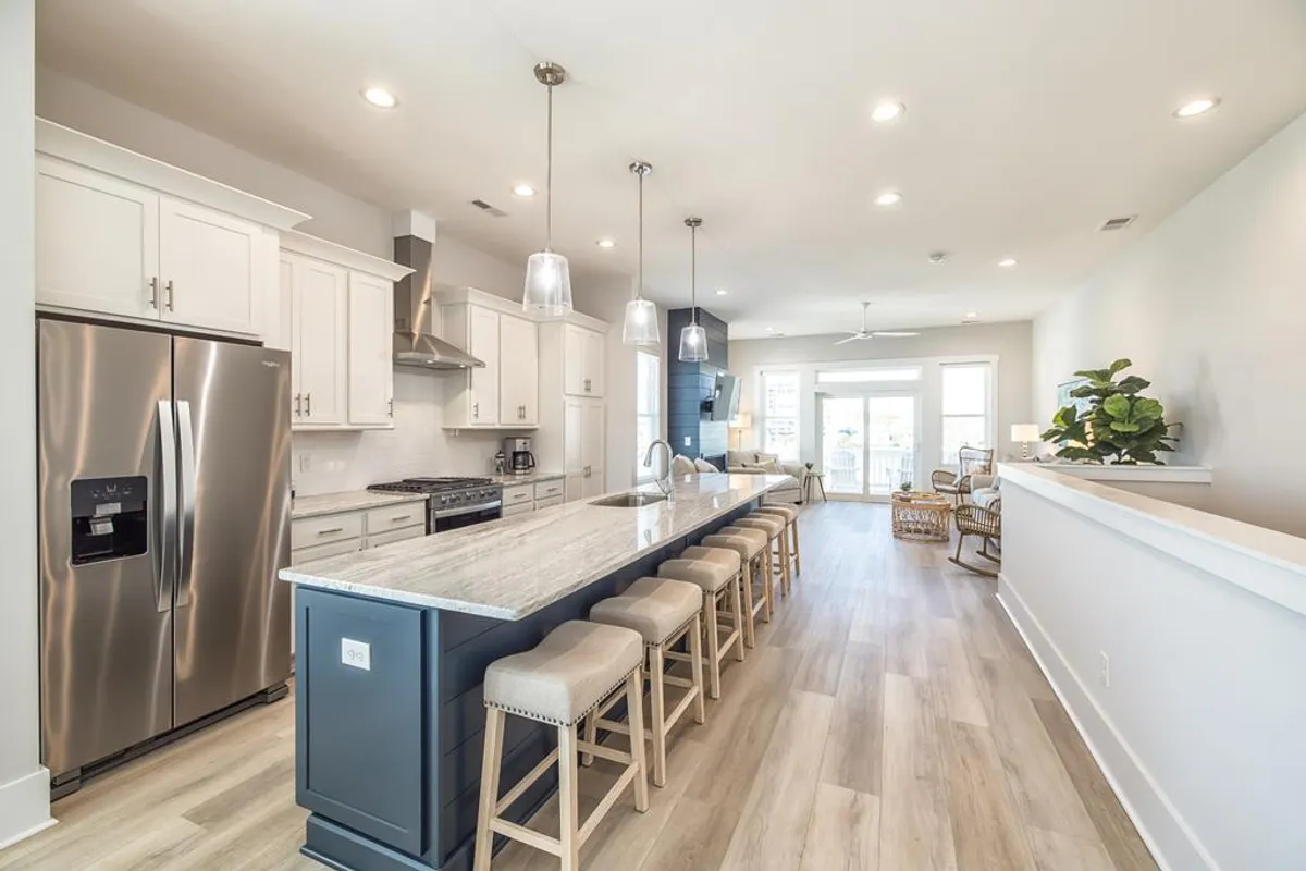 This image captures a spacious, open-concept kitchen with a large granite island featuring bar seating. Stainless steel appliances, modern light fixtures, and a flowing layout that connects to living and dining spaces are visible. The welcoming setup makes it ideal for group gatherings and culinary experiences.