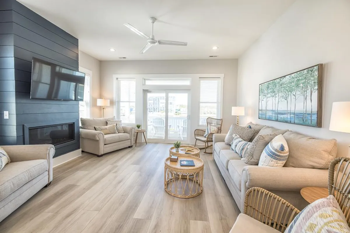 A plush, inviting living room with a cozy sofa, armchairs, and a coffee table faces large windows that draw in abundant light and offer views outside. The ambiance is perfect for relaxing, socializing, or enjoying the view—emphasizing comfort and togetherness.